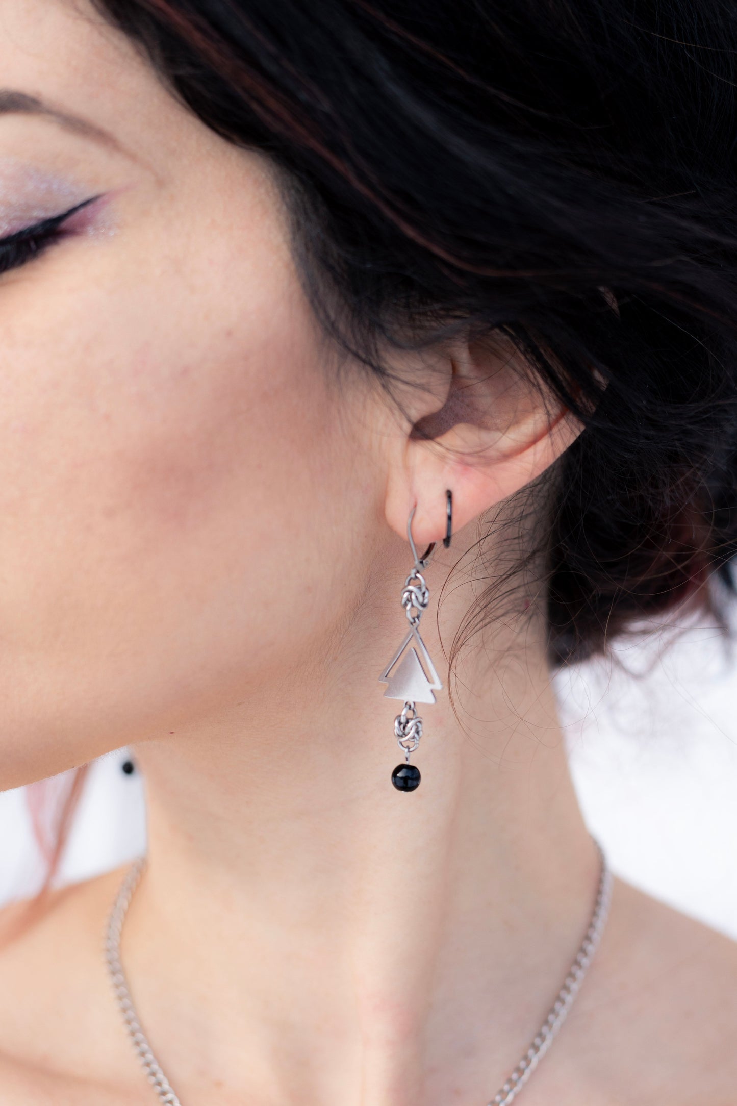 Pair of earrings on a stand with a blurred natural background