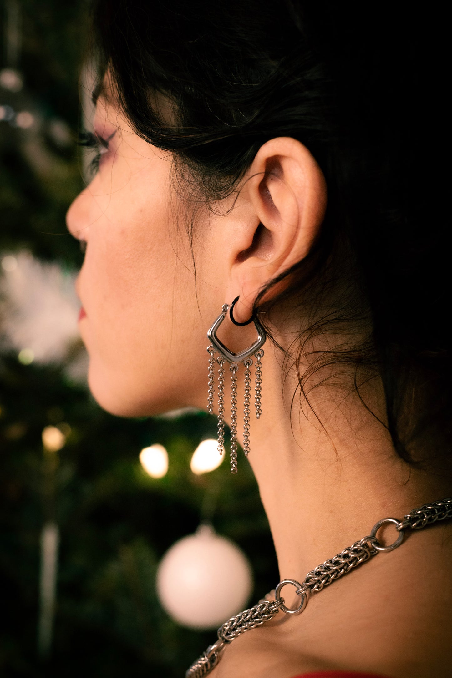 Silver hoop earrings with dangling chains on a dark background