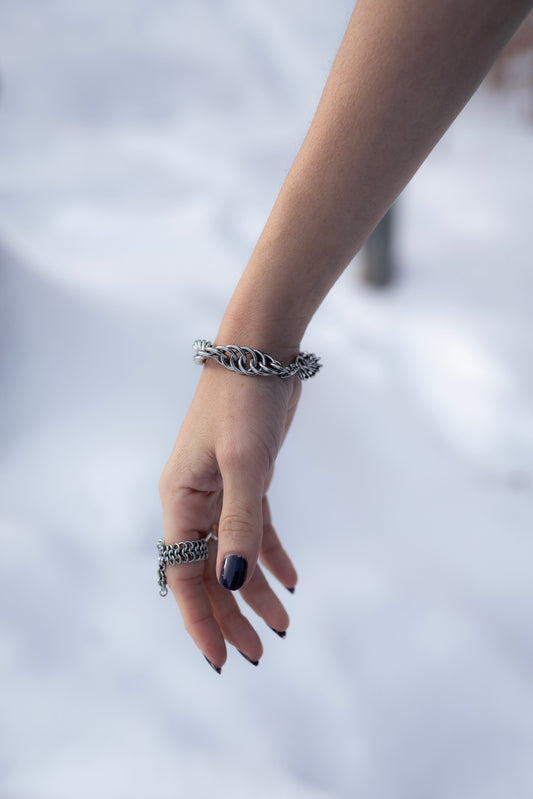 GAÏA | Chainmail Bold Bracelet
Hand wearing multiple silver bracelets on a blurred background