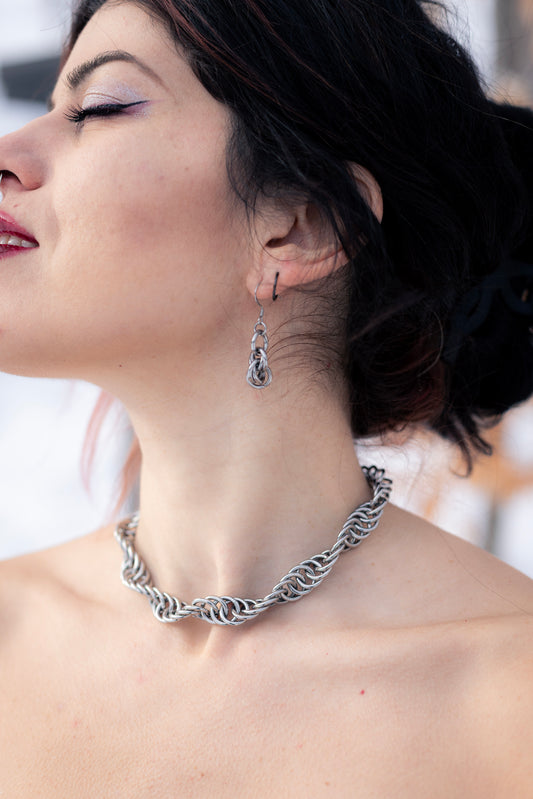 GAÏA | Chainmail Bold Necklace
Close-up of a woman wearing a stainless steel twisted necklace with a blurred outdoor background.