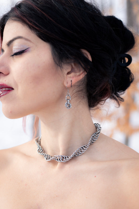 GAÏA | Chainmail Bold Necklace
Close-up of a woman wearing a stainless steel twisted necklace with a blurred outdoor background.
