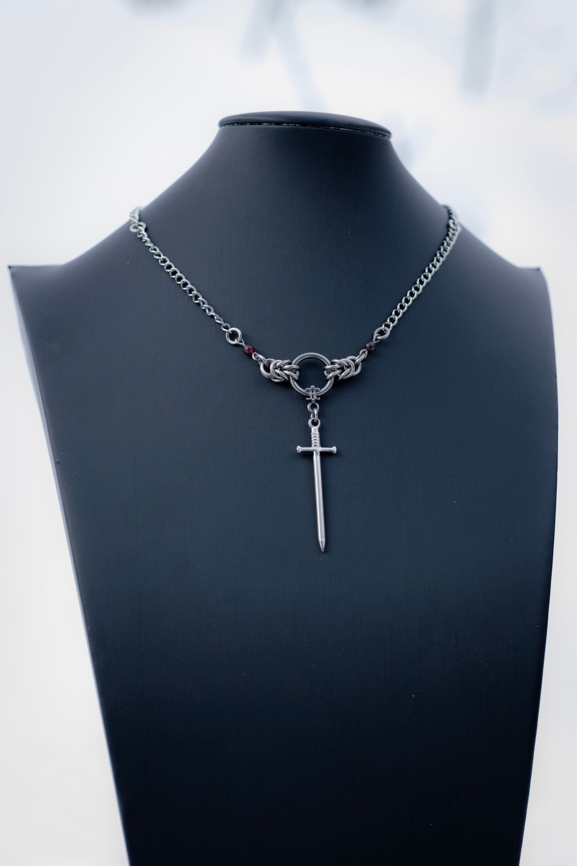 ARYA | Chainmail Earrings
Stainless steel chainmail earrings with a garnet stone and a silver sword