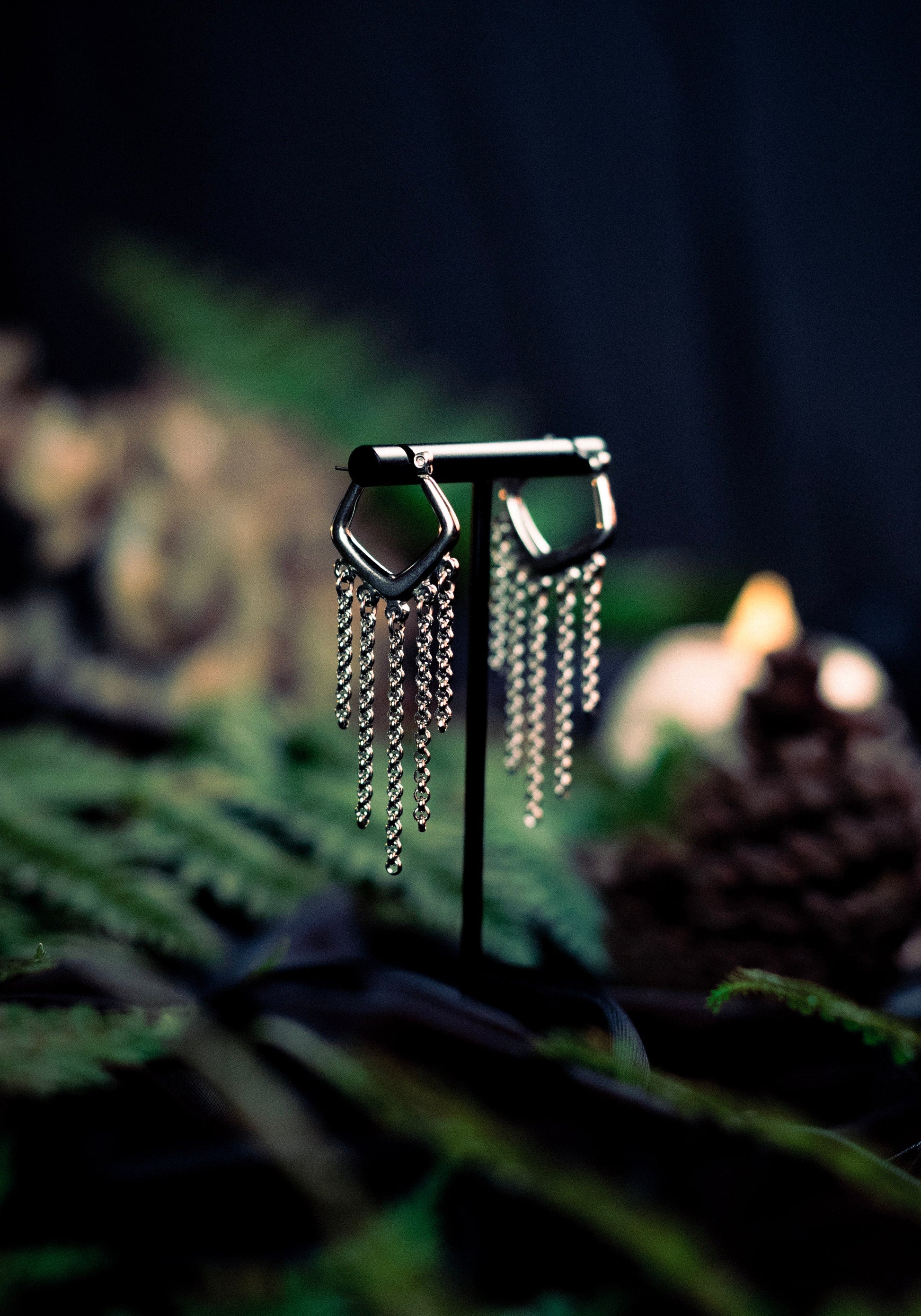 Silver hoop earrings with dangling chains on a dark background