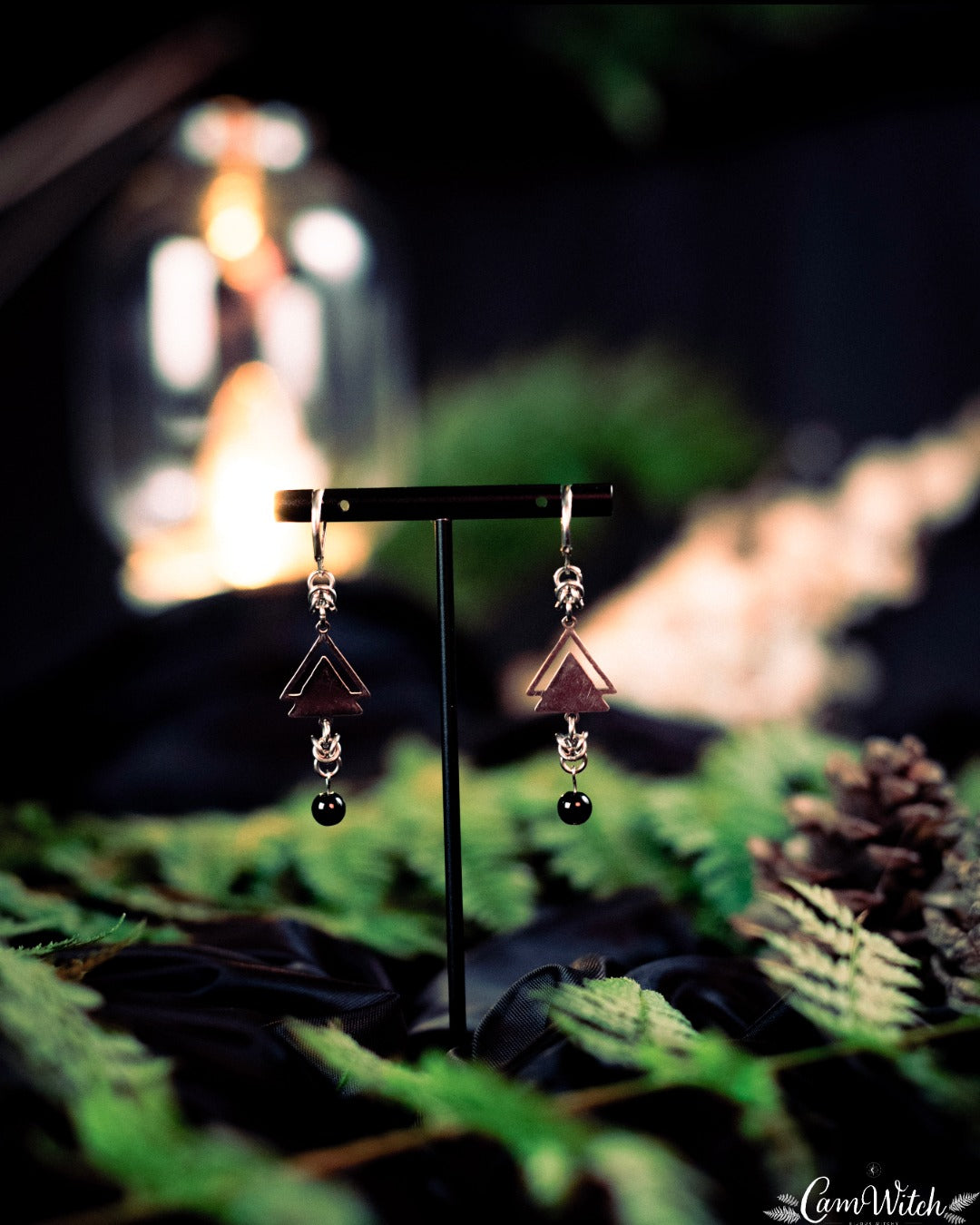 Pair of earrings on a stand with a blurred natural background