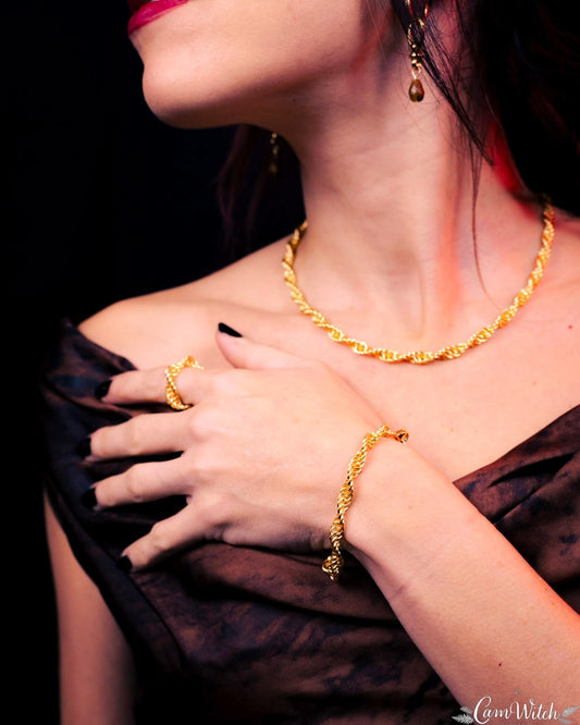 Close-up of a person wearing gold jewelry including a necklace, ring, and bracelet.