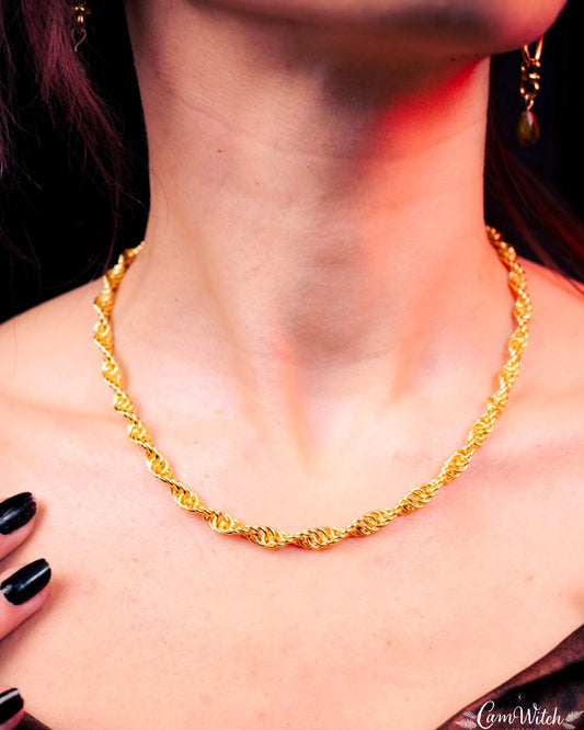 Gold necklace worn by a person with a blurred background